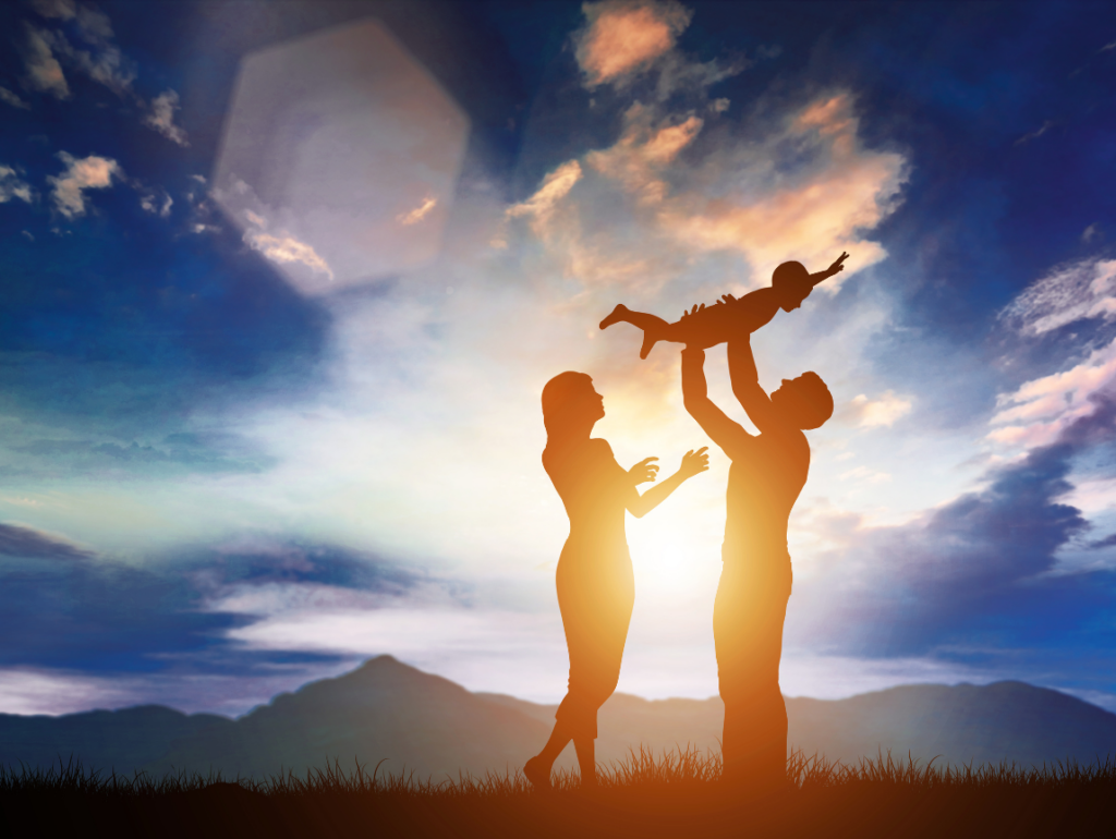 Parents lifting their child into the air at sunset