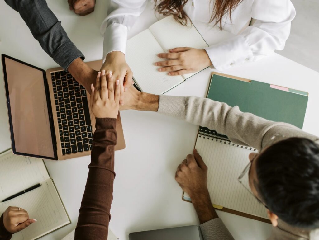 Colleagues joining hands over a meeting table